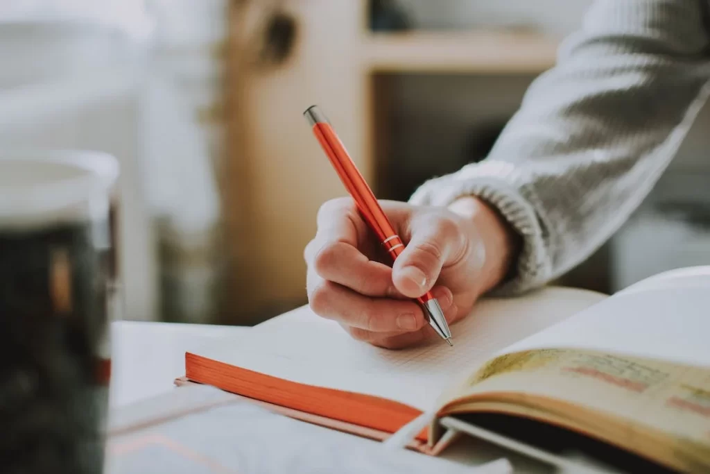 person-holding-orange-pen