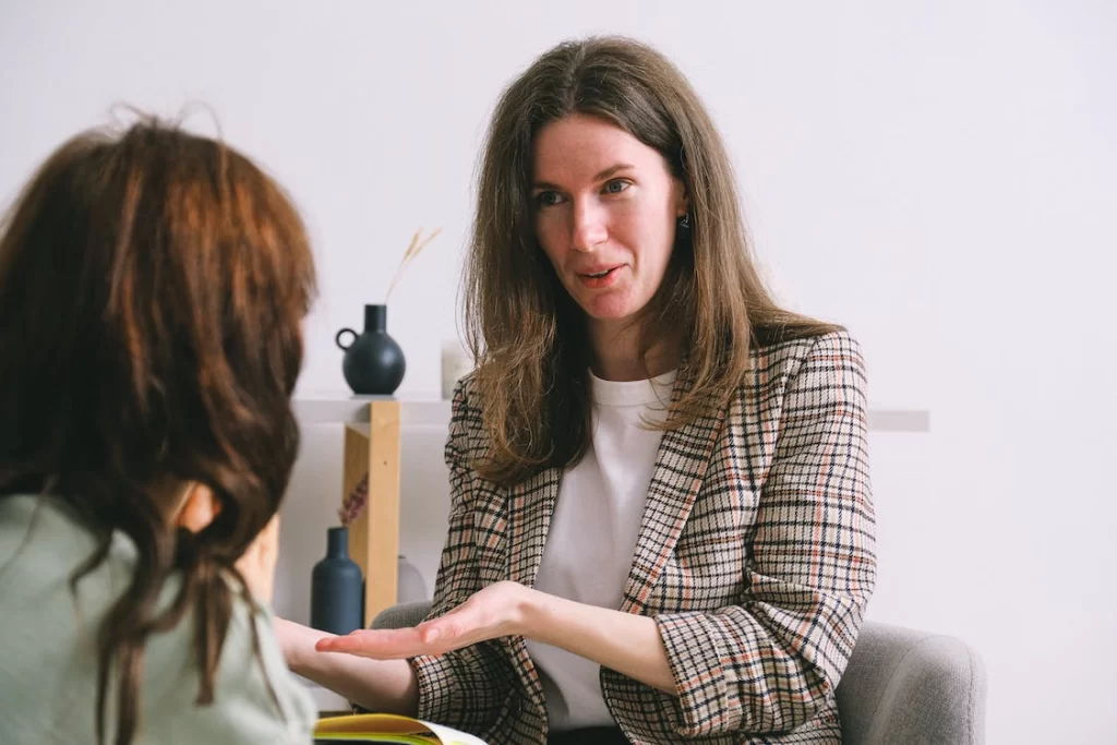 smiling-therapist-speaking-with-anonymous-female-patient-in-light-office